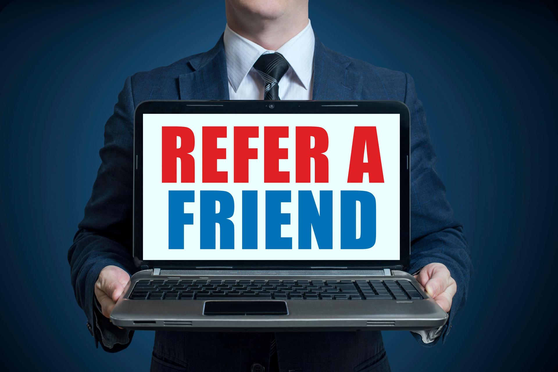 Businessman holding a laptop with text REFER A FRIEND